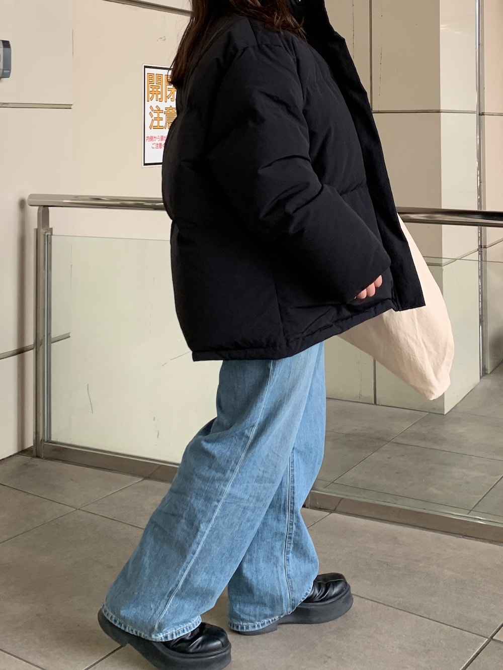 ブラック系のダウンジャケット/コート、グリーン系のニット/セーター、ブルー系のデニムパンツを着用したレディースの冬コーディネートの5枚目の写真