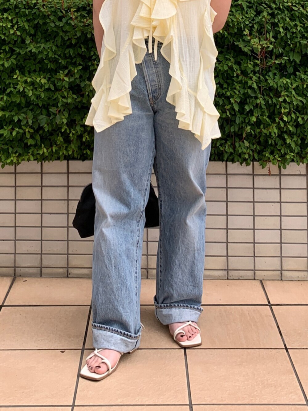 ブルー系のデニムパンツ、イエロー系のキャミソール、ホワイト系のタンクトップを着用したレディースの夏コーディネートの5枚目の写真