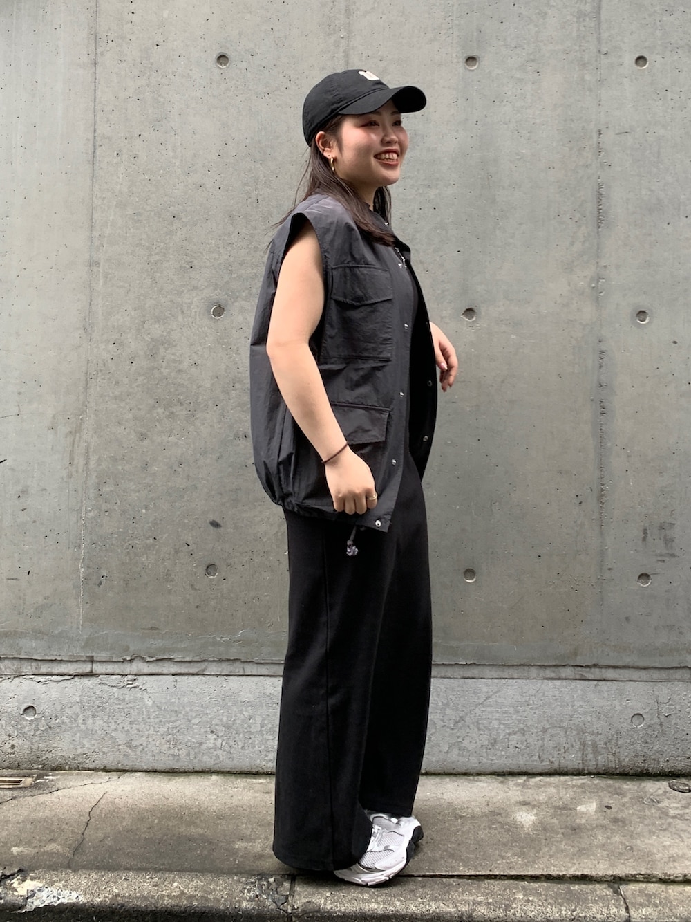 グレー系のベスト、ブラック系のワンピースを着用したレディースの春コーディネートの2枚目の写真