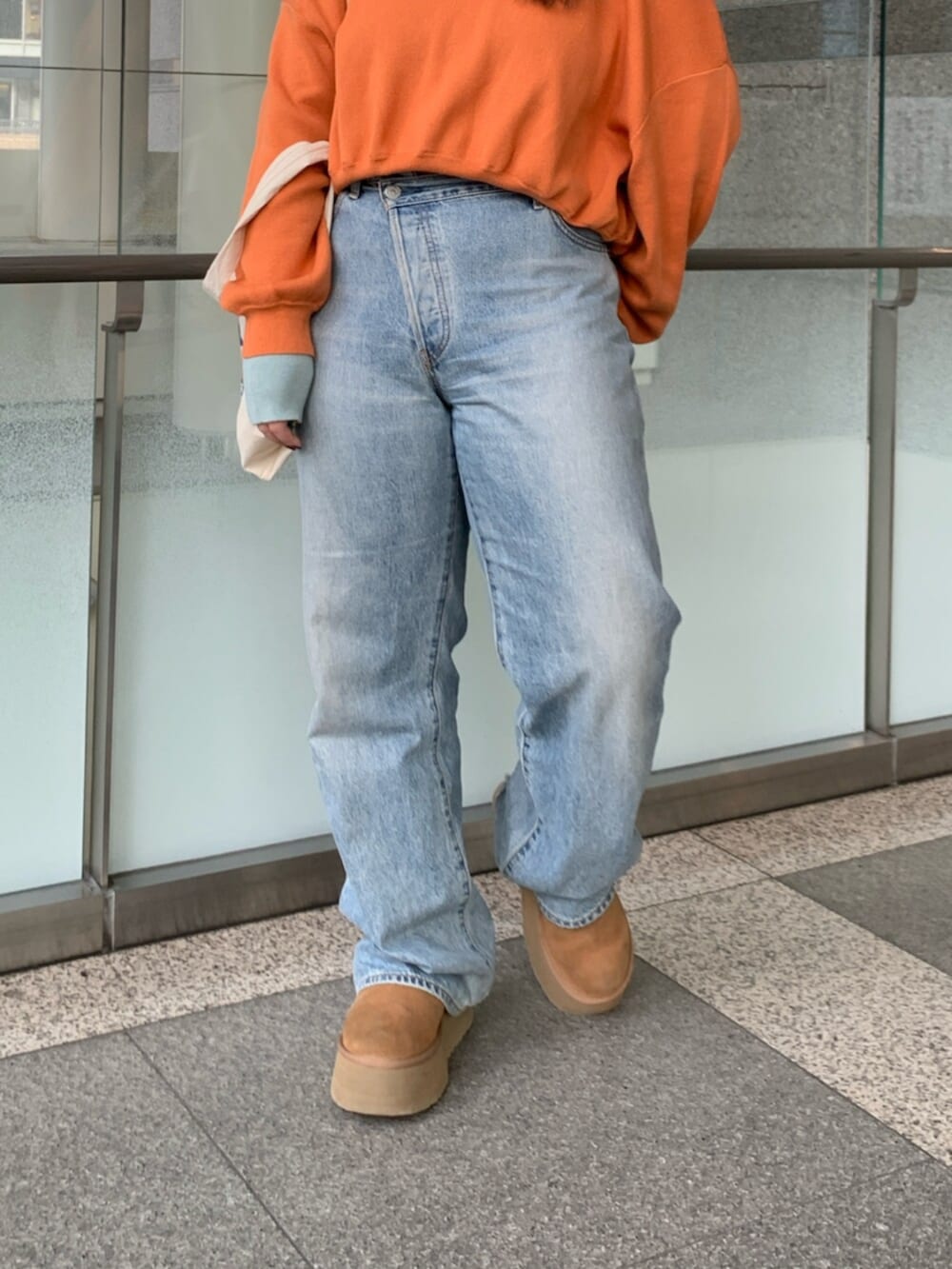 オレンジ系のニット/セーター、ブルー系のデニムパンツ、ホワイト系のトートバッグを着用したレディースの冬コーディネートの6枚目の写真