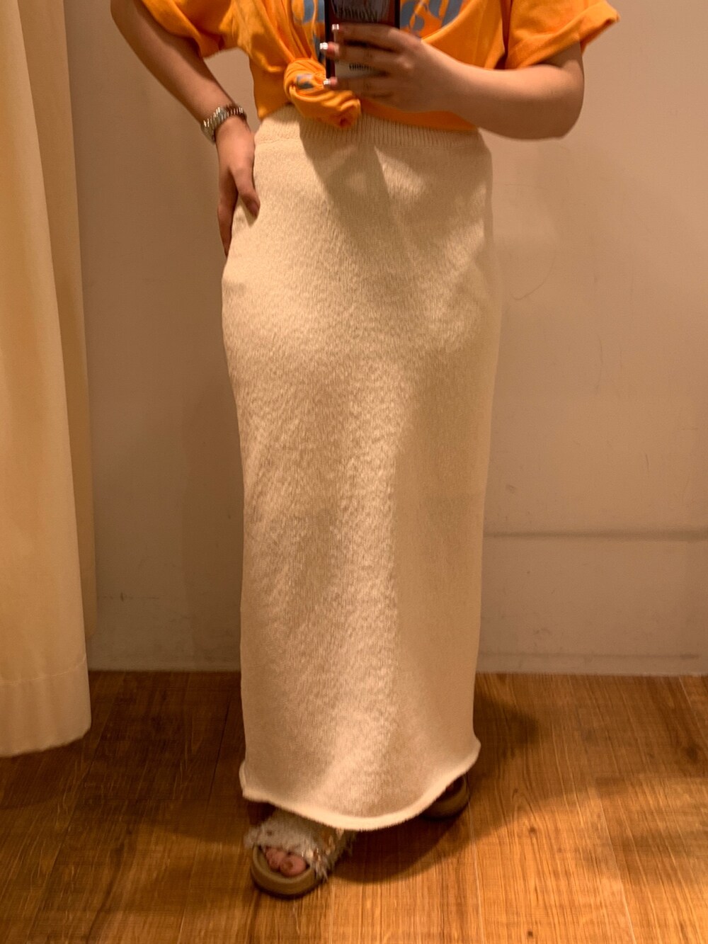 オレンジ系のTシャツ/カットソー、ホワイト系のスカート、ベージュ系のトートバッグを着用したレディースの春コーディネートの5枚目の写真