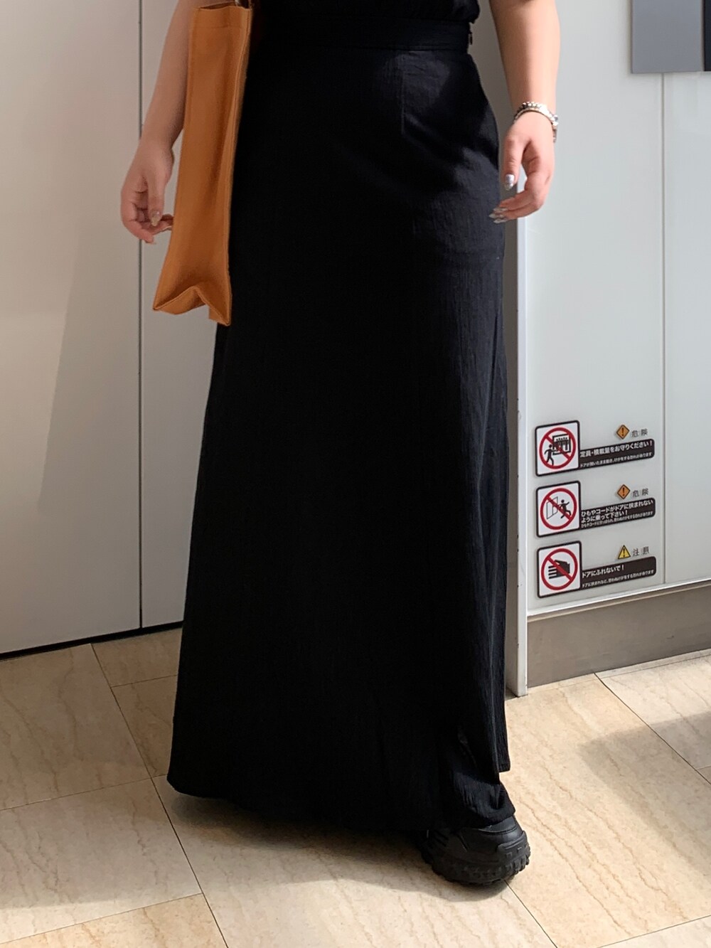 ブラック系のワンピース、オレンジ系のトートバッグを着用したレディースの春コーディネートの6枚目の写真