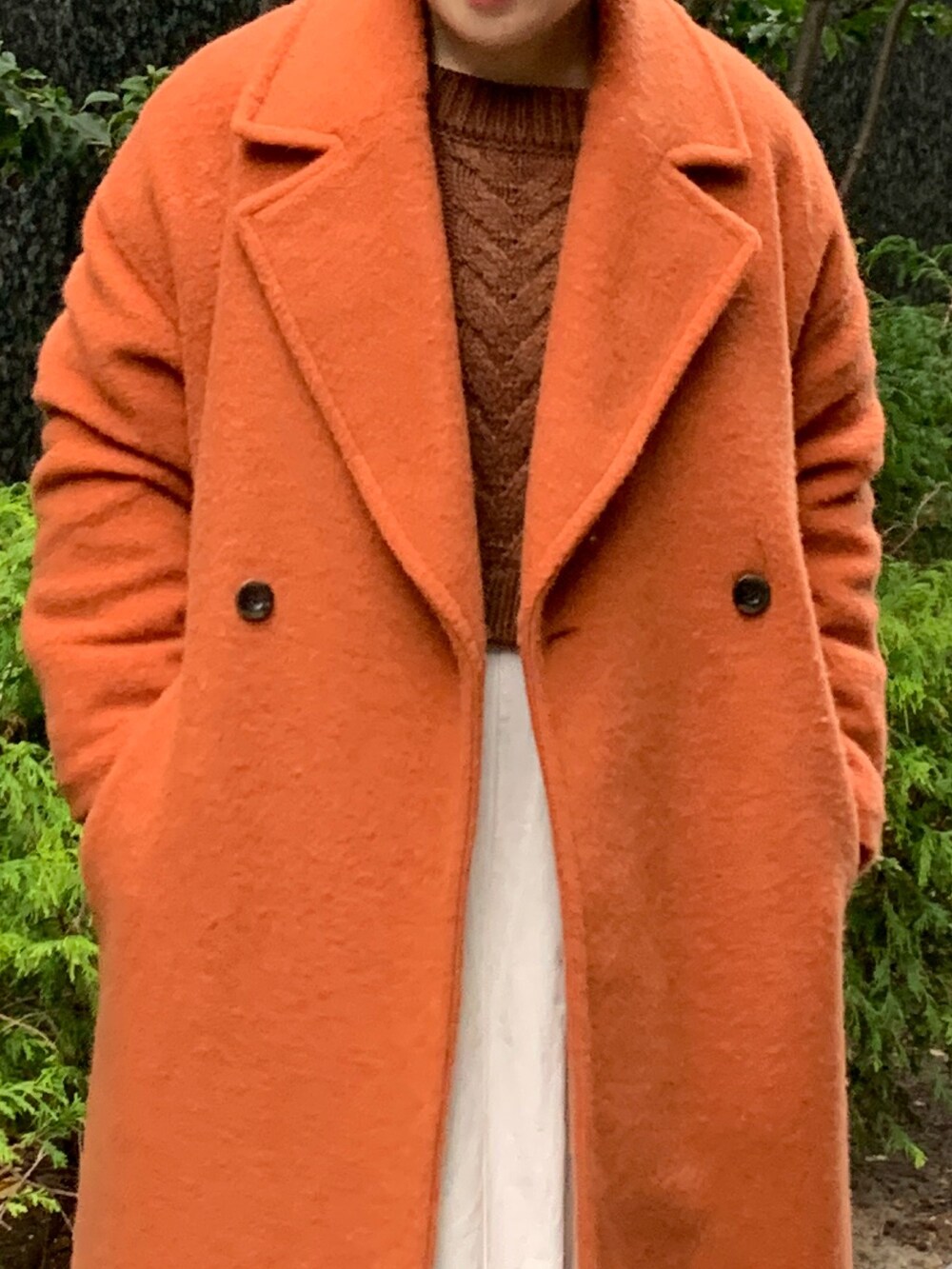 ブラウン系のニット/セーター、ブラック系のワンピース、オレンジ系のチェスターコートを着用したレディースの冬コーディネートの7枚目の写真