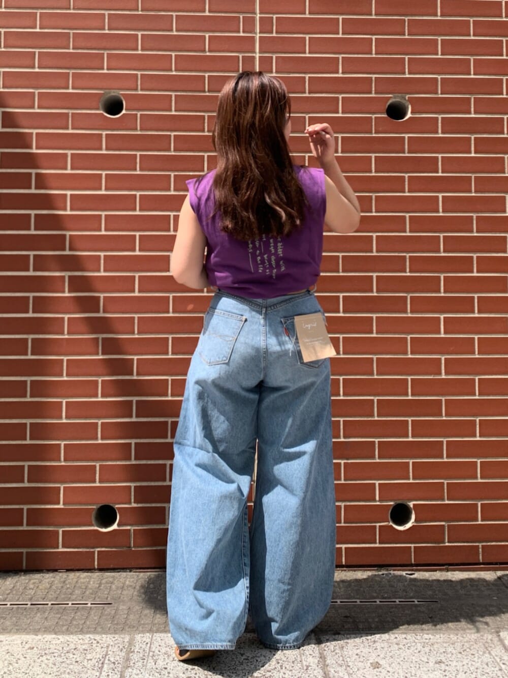 パープル系のタンクトップ、ブルー系のデニムパンツを着用したレディースの夏コーディネートの3枚目の写真