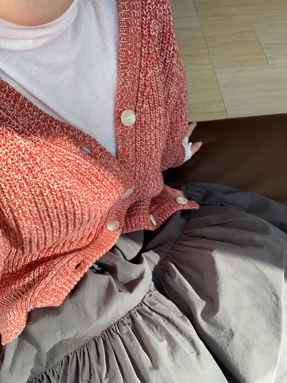 ピンク系のTシャツ/カットソー、オレンジ系のカーディガン/ボレロ、グレー系のスカートを着用したレディースの冬コーディネートの4枚目の写真