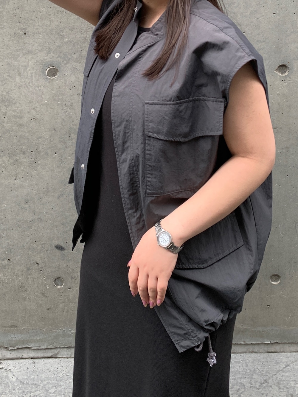 グレー系のベスト、ブラック系のワンピースを着用したレディースの春コーディネートの8枚目の写真