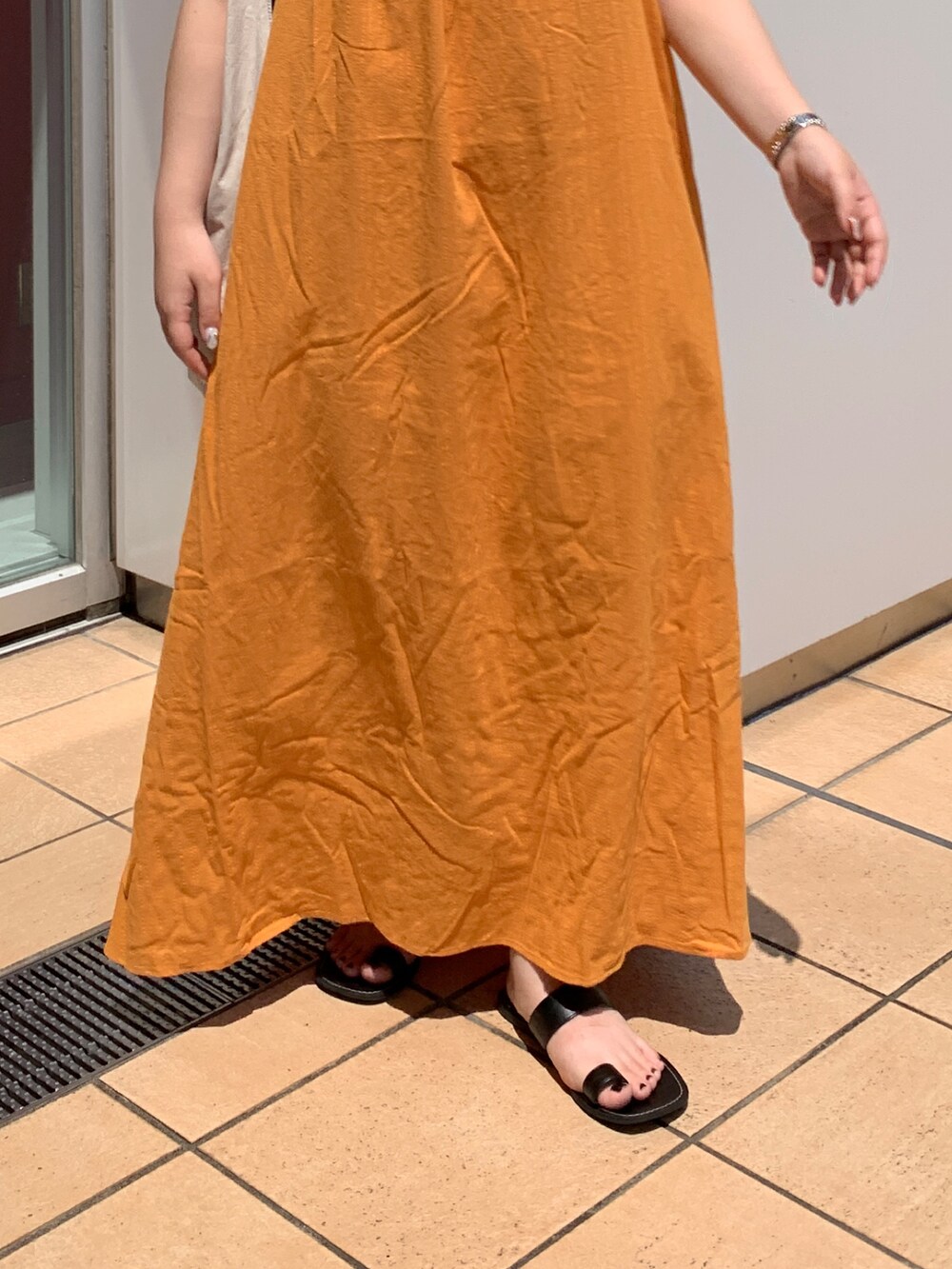 オレンジ系のワンピース、ホワイト系のハンドバッグを着用したレディースの夏コーディネートの5枚目の写真