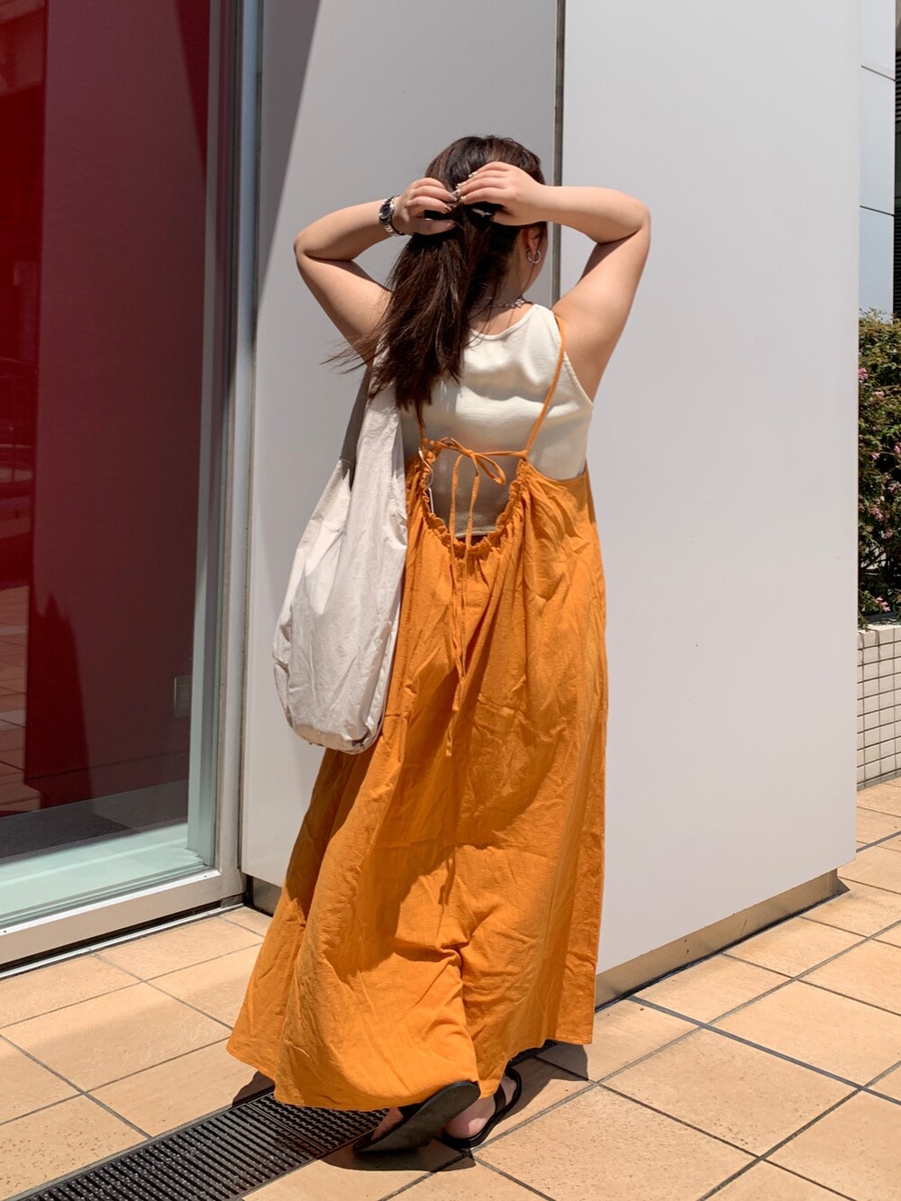 オレンジ系のワンピース、ホワイト系のハンドバッグを着用したレディースの夏コーディネートの3枚目の写真