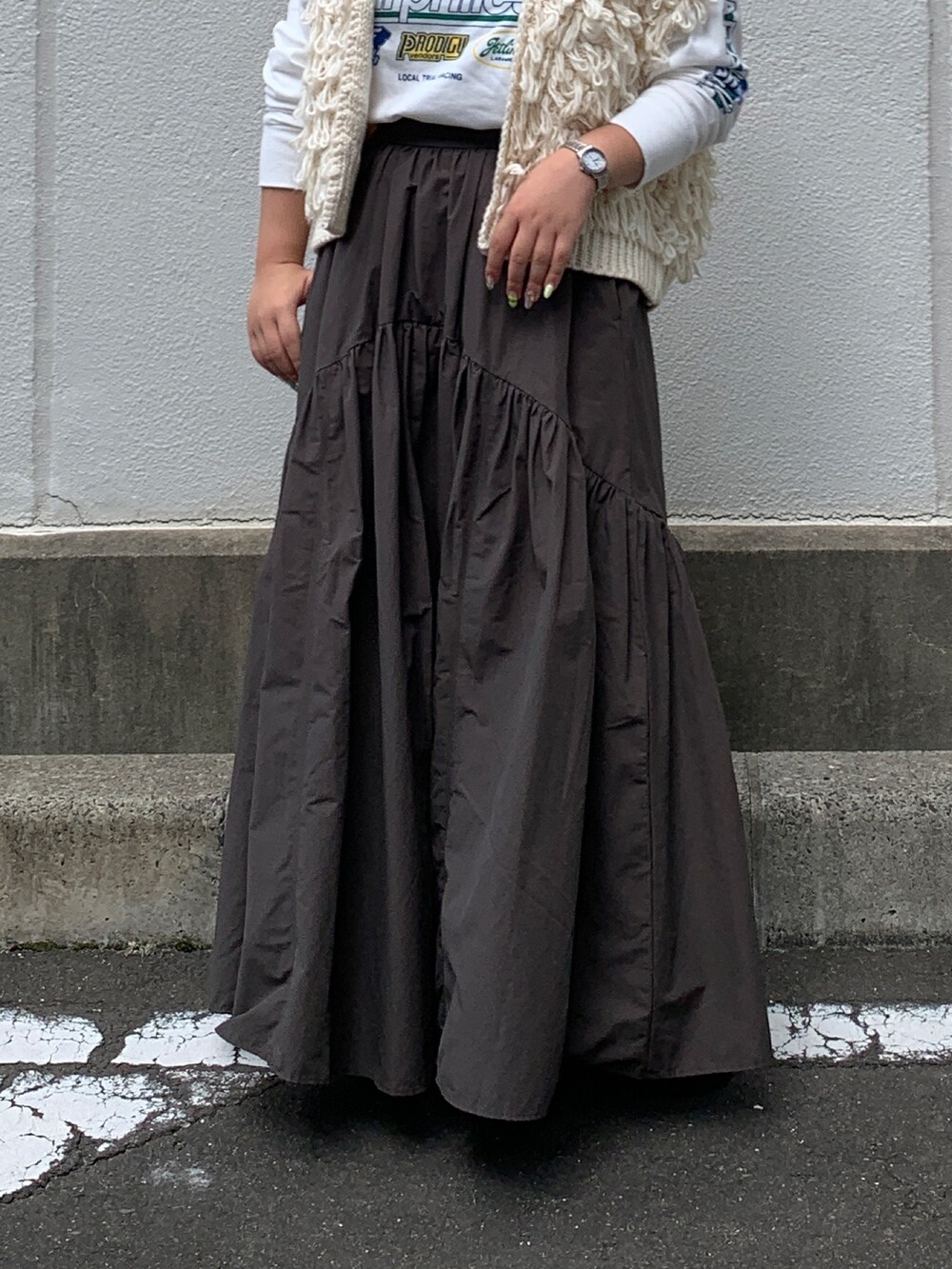 ホワイト系のTシャツ/カットソー、ホワイト系のベスト、グレー系のスカートを着用したレディースの秋コーディネートの5枚目の写真