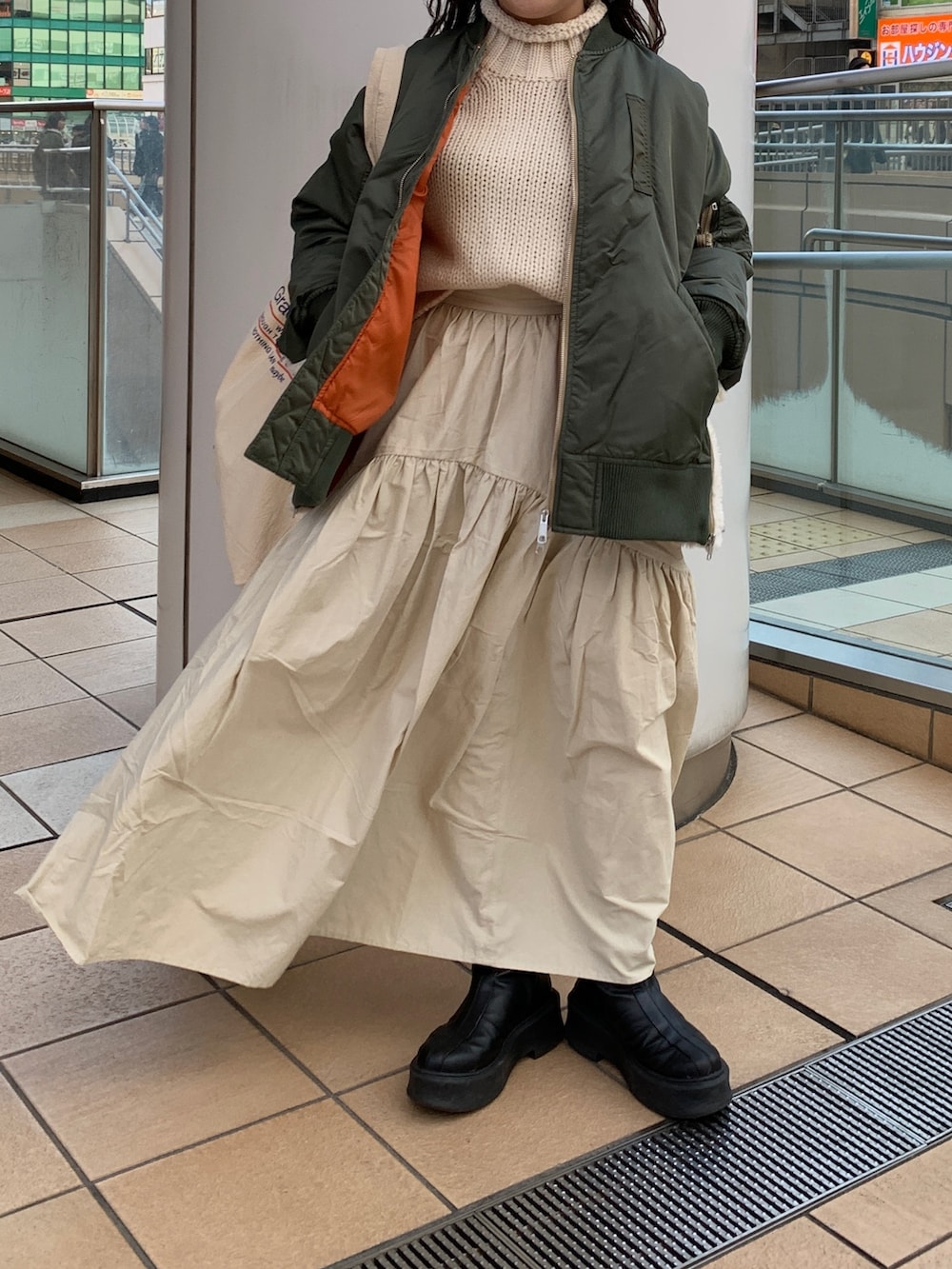 ホワイト系のスカート、ホワイト系のニット/セーター、グリーン系のMA-1を着用したレディースの冬コーディネートの5枚目の写真