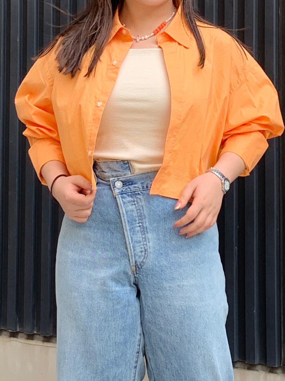 オレンジ系のシャツ/ブラウス、ホワイト系のキャミソール、ブルー系のデニムパンツを着用したレディースの春コーディネートの4枚目の写真