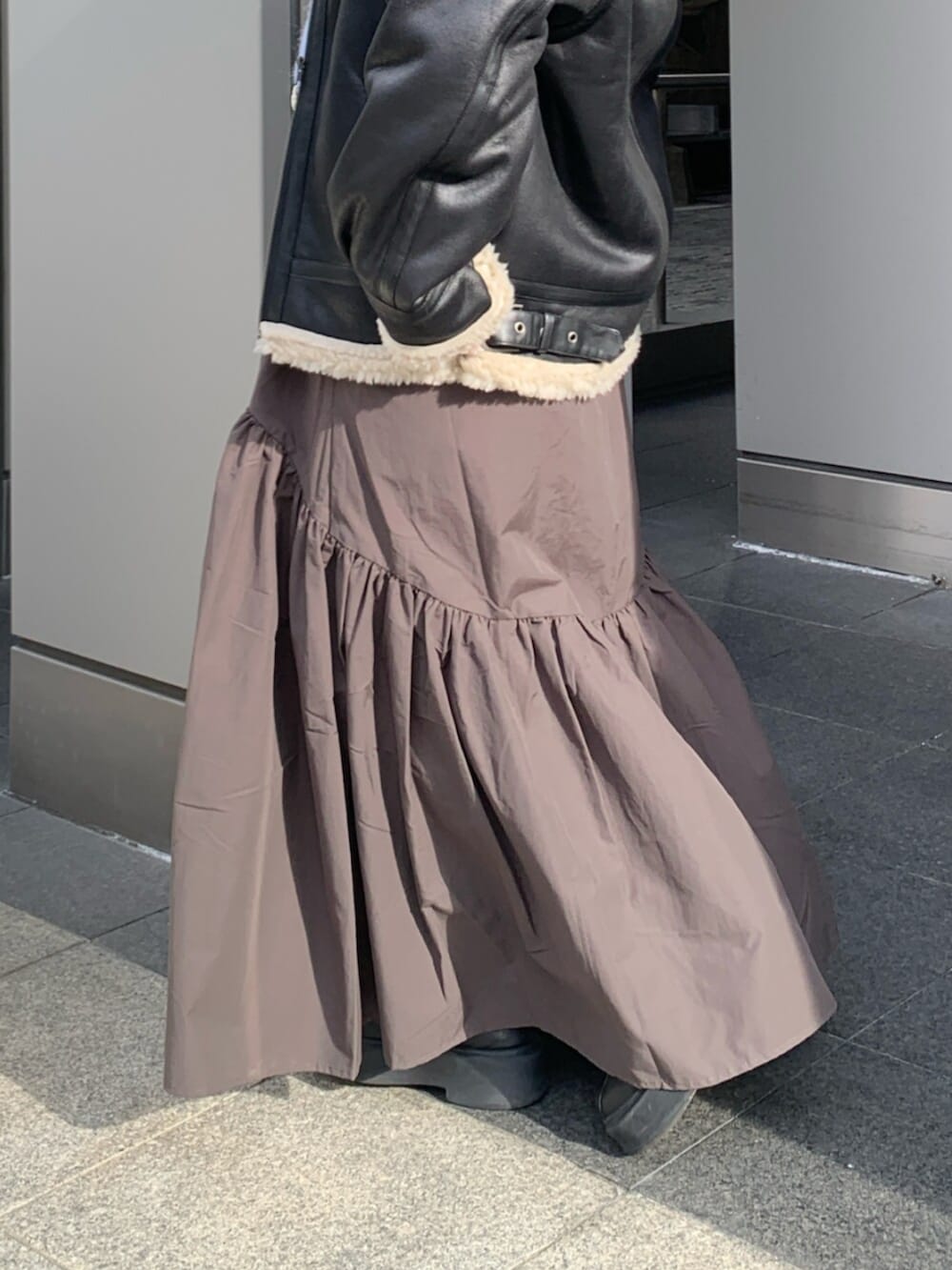 グレー系のスカート、ブラック系のブルゾン、ブルー系のニット/セーターを着用したレディースの冬コーディネートの6枚目の写真