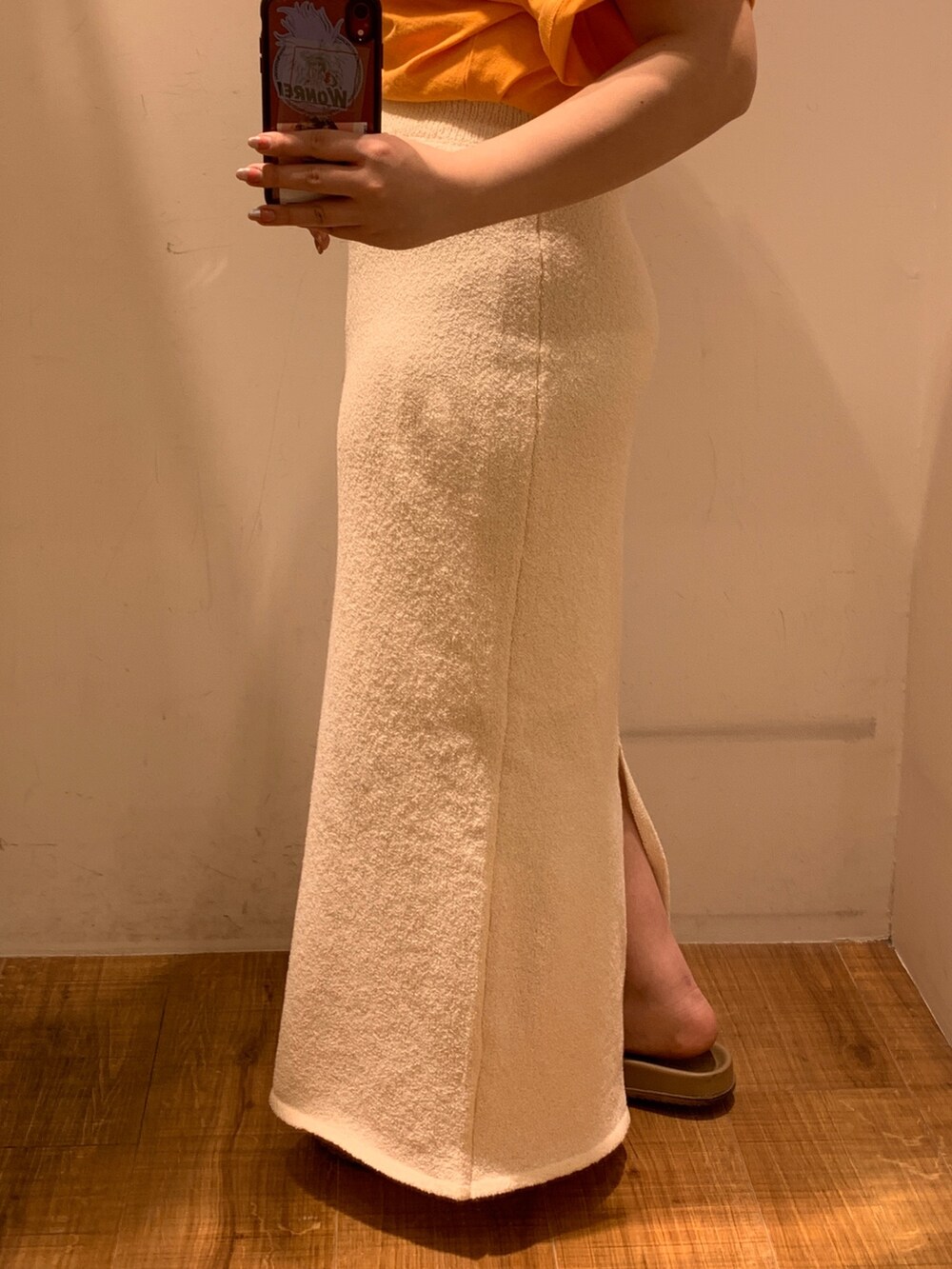 オレンジ系のTシャツ/カットソー、ホワイト系のスカート、ベージュ系のトートバッグを着用したレディースの春コーディネートの6枚目の写真