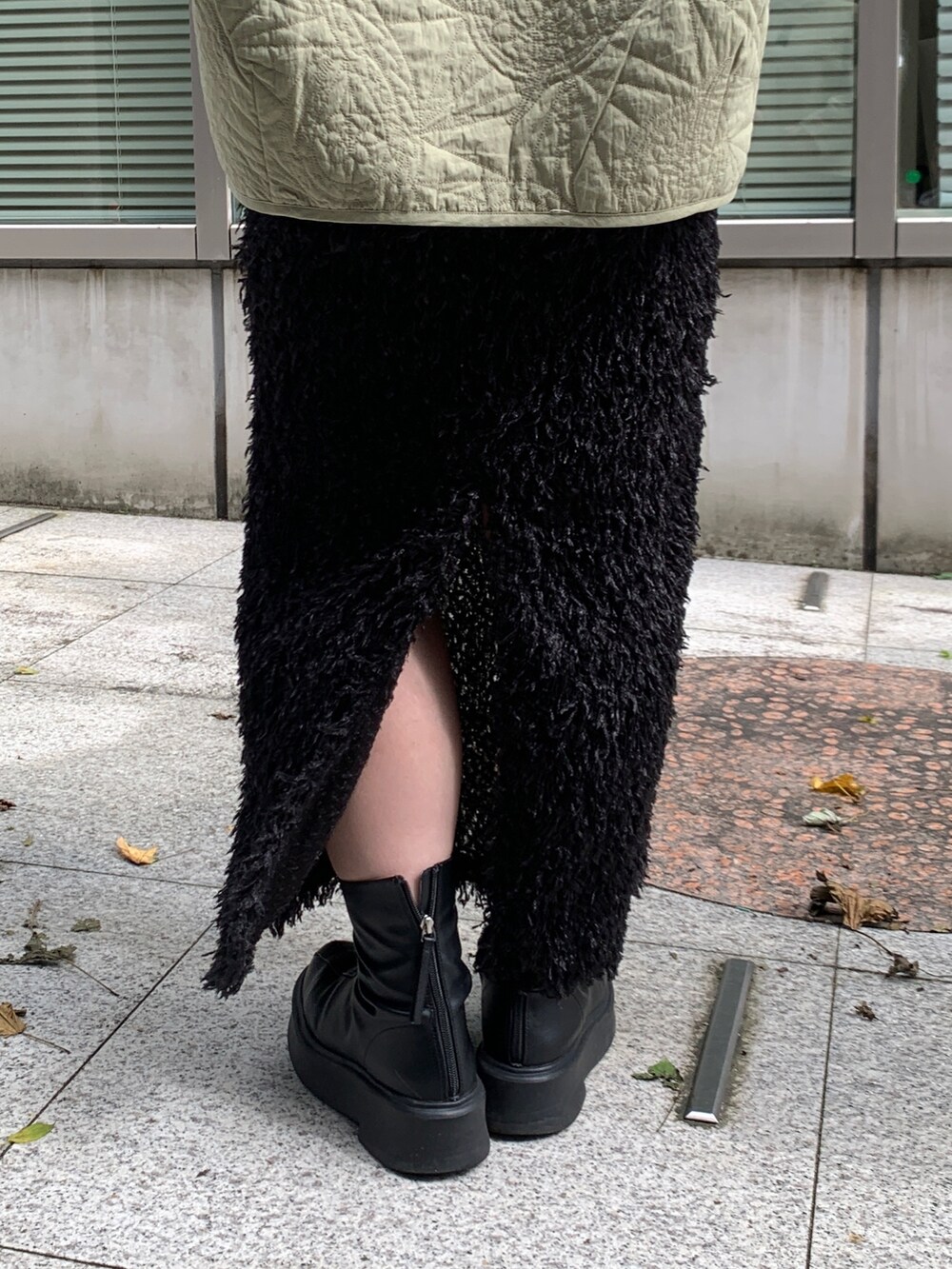 グリーン系のブルゾン、ホワイト系のTシャツ/カットソー、ブラック系のスカートを着用したレディースの秋コーディネートの6枚目の写真