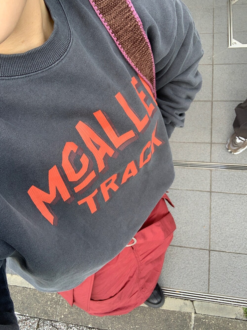 グレー系のスウェット、レッド系のスカート、ブラウン系のハンドバッグを着用したレディースの冬コーディネートの4枚目の写真