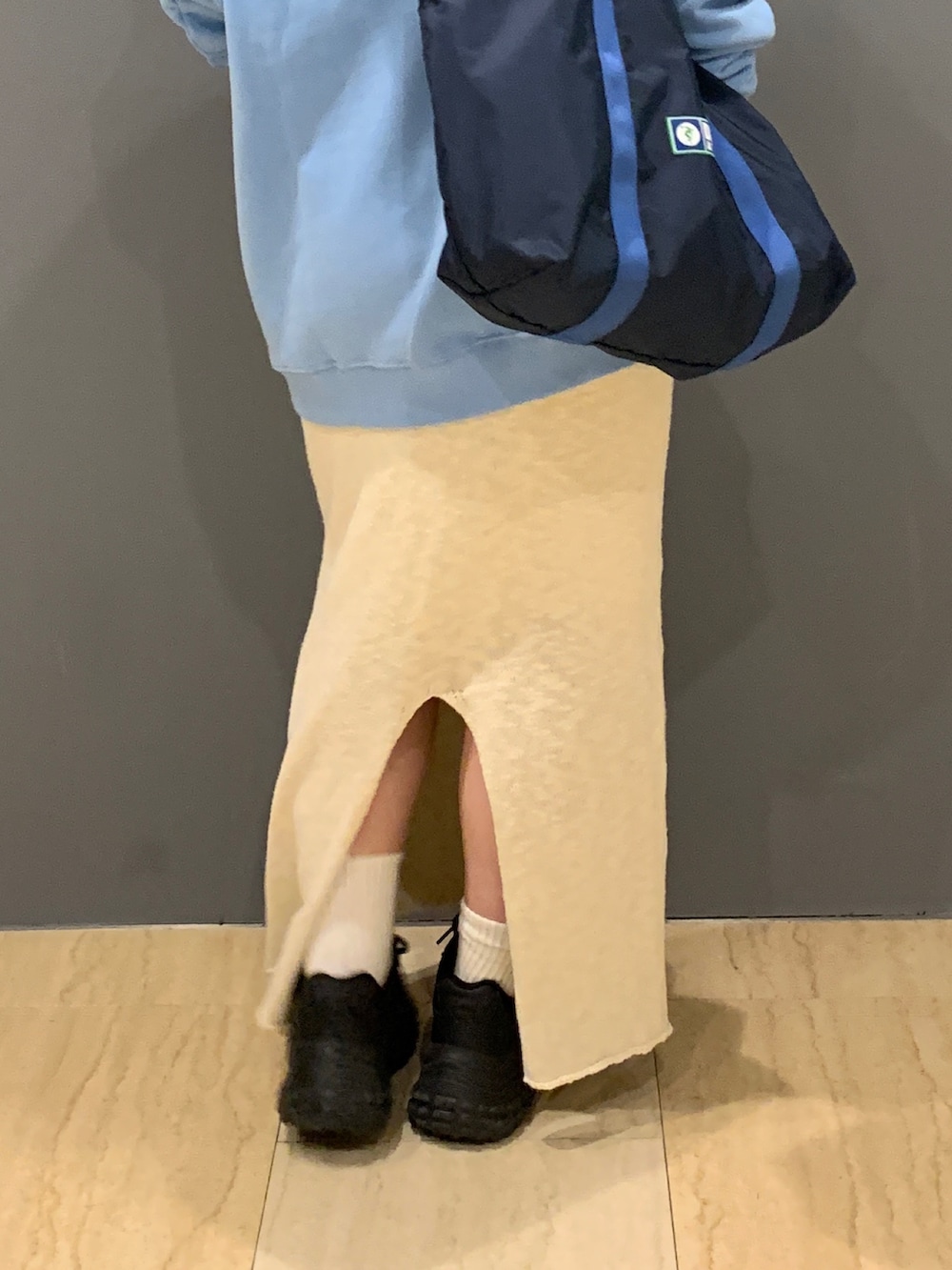 ブルー系のパーカー、ホワイト系のスカート、ブルー系のトートバッグを着用したレディースの冬コーディネートの7枚目の写真