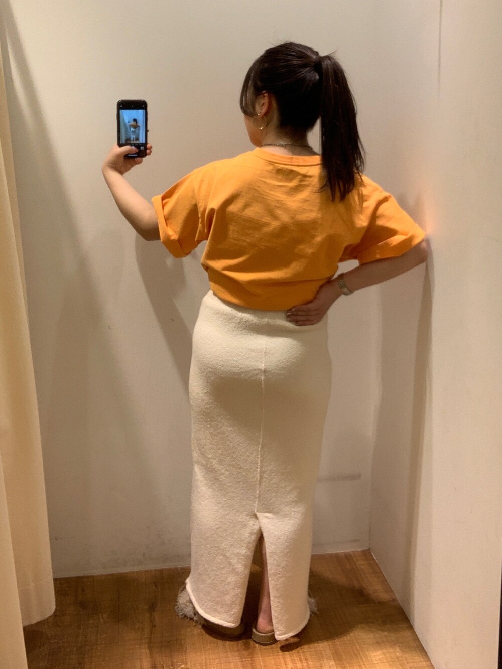 オレンジ系のTシャツ/カットソー、ホワイト系のスカート、ベージュ系のトートバッグを着用したレディースの春コーディネートの3枚目の写真