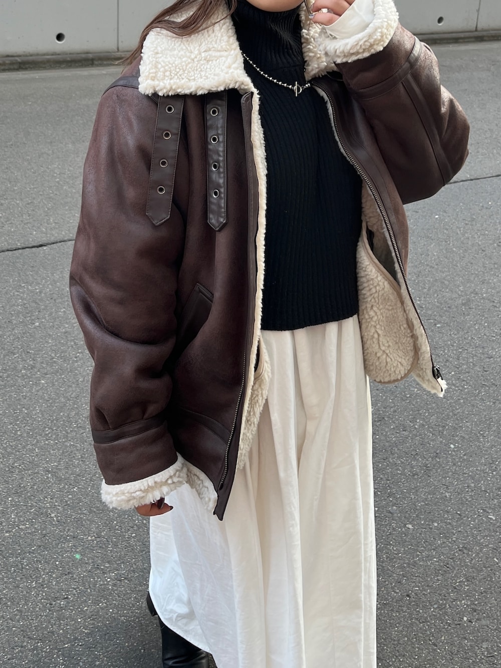 ブラウン系のムートンコート、ブラック系のワンピースを着用したレディースの秋コーディネートの3枚目の写真