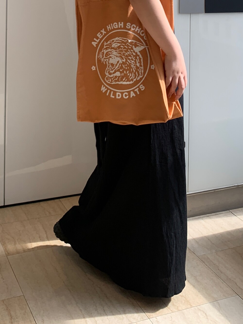 ブラック系のワンピース、オレンジ系のトートバッグを着用したレディースの春コーディネートの7枚目の写真