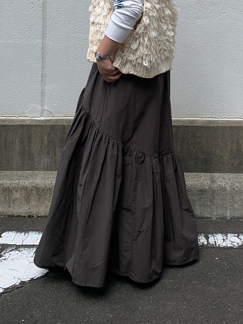 ホワイト系のTシャツ/カットソー、ホワイト系のベスト、グレー系のスカートを着用したレディースの秋コーディネートの6枚目の写真