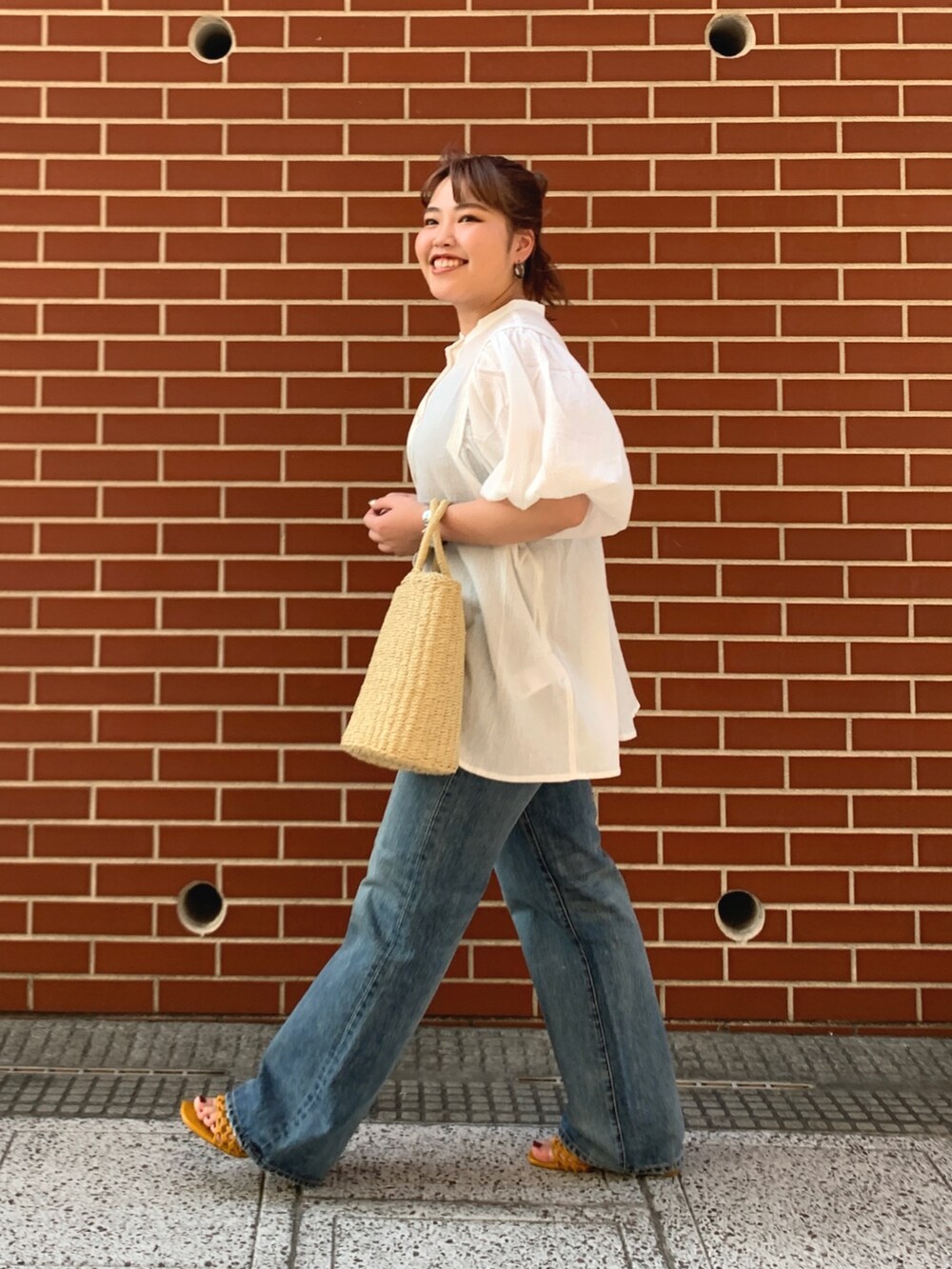 ブルー系のデニムパンツ、ベージュ系のかごバッグ、ホワイト系のシャツ/ブラウスを着用したレディースの夏コーディネートの2枚目の写真