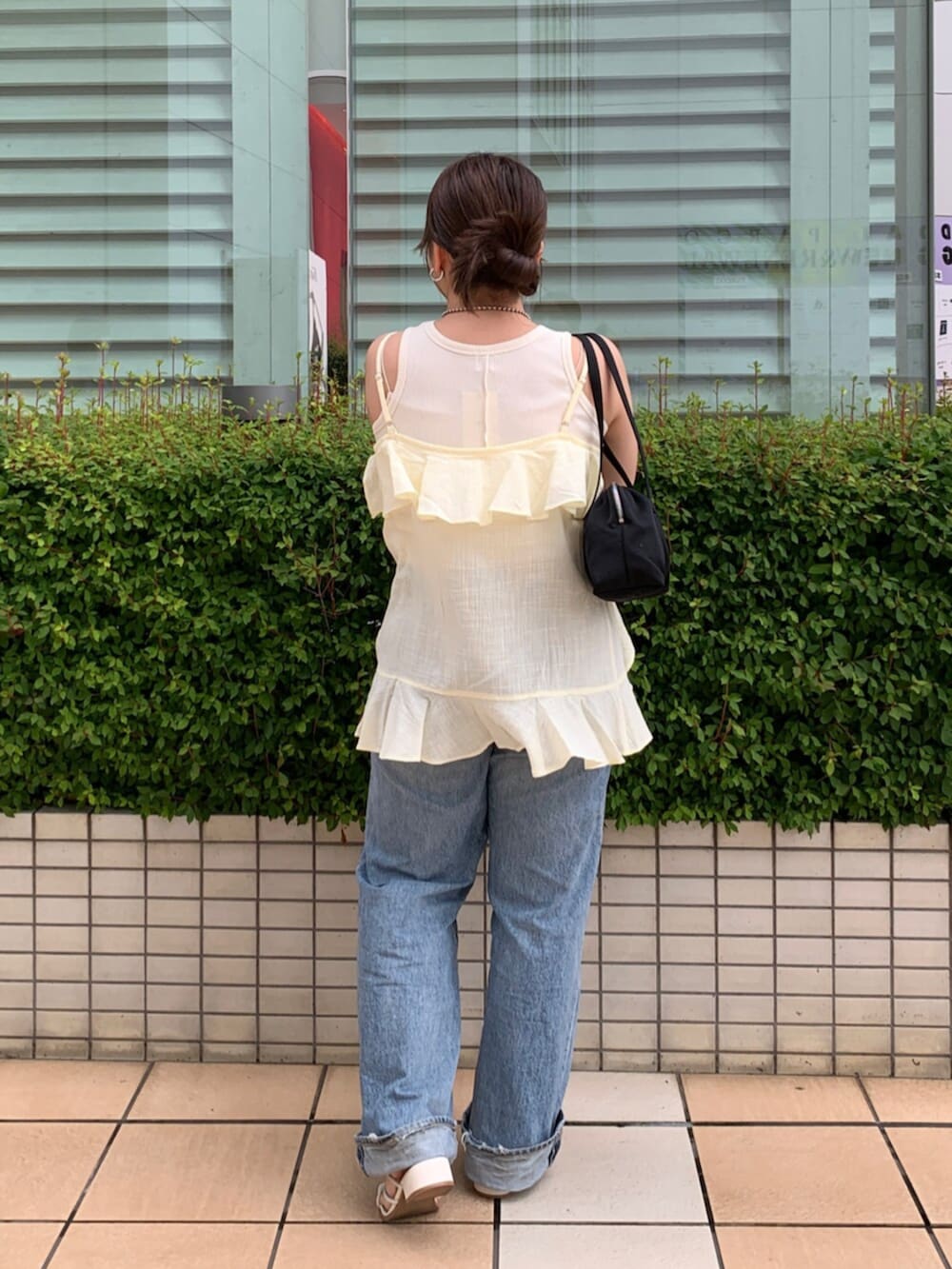 ブルー系のデニムパンツ、イエロー系のキャミソール、ホワイト系のタンクトップを着用したレディースの夏コーディネートの3枚目の写真