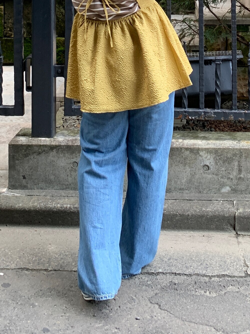 イエロー系のキャミソール、ブラウン系のTシャツ/カットソー、ブルー系のデニムパンツを着用したレディースの秋コーディネートの7枚目の写真