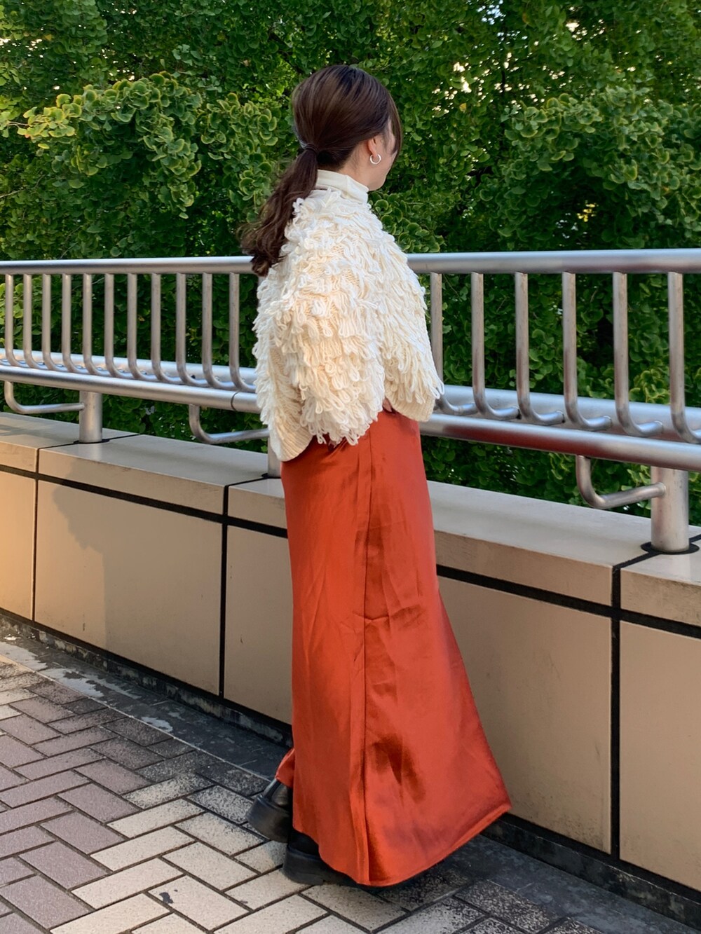 ホワイト系のカーディガン/ボレロ、ホワイト系のTシャツ/カットソー、オレンジ系のスカートを着用したレディースの冬コーディネートの2枚目の写真