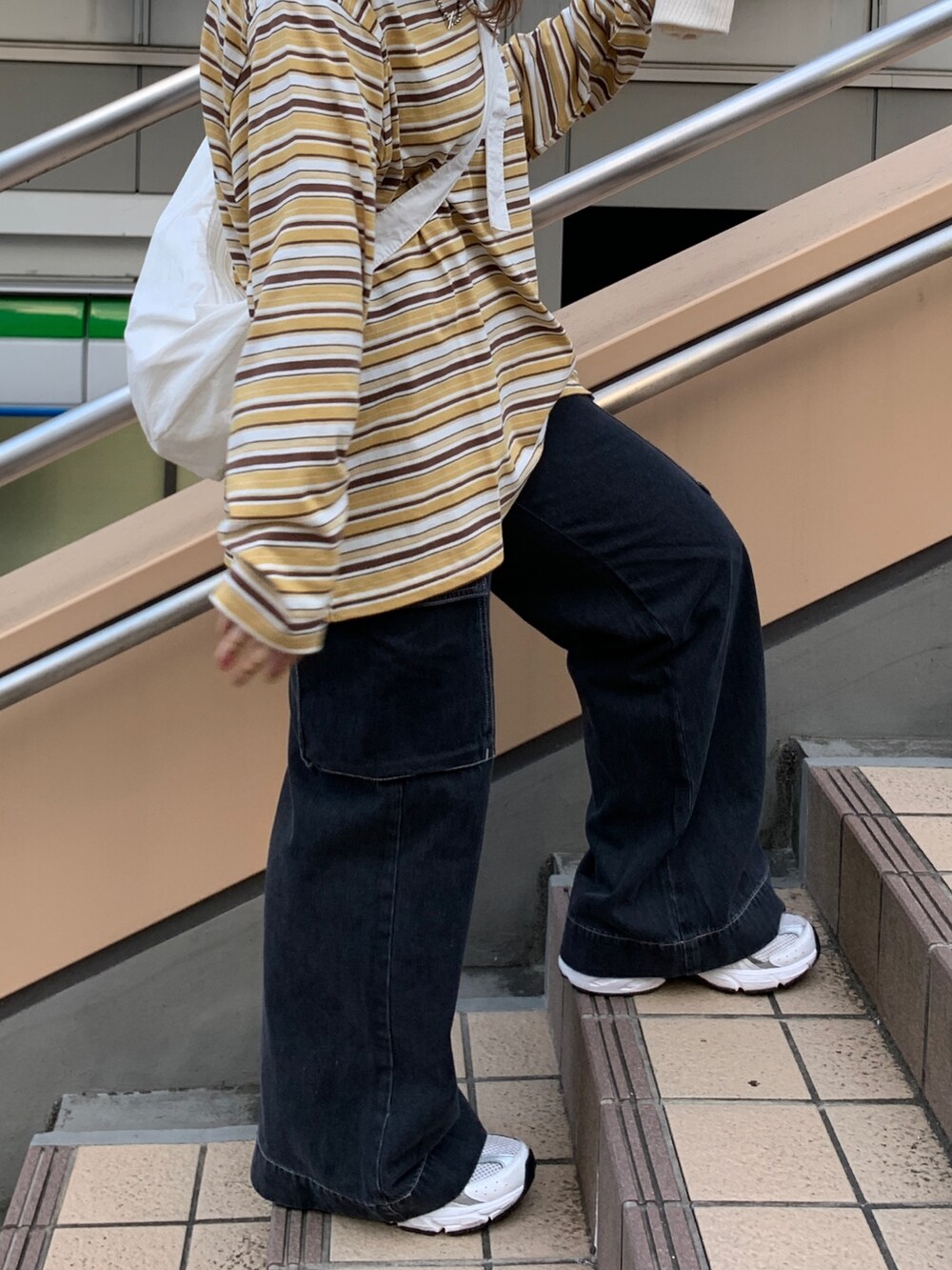 イエロー系のTシャツ/カットソー、ブラック系のデニムパンツ、ホワイト系のショルダーバッグを着用したレディースの秋コーディネートの3枚目の写真