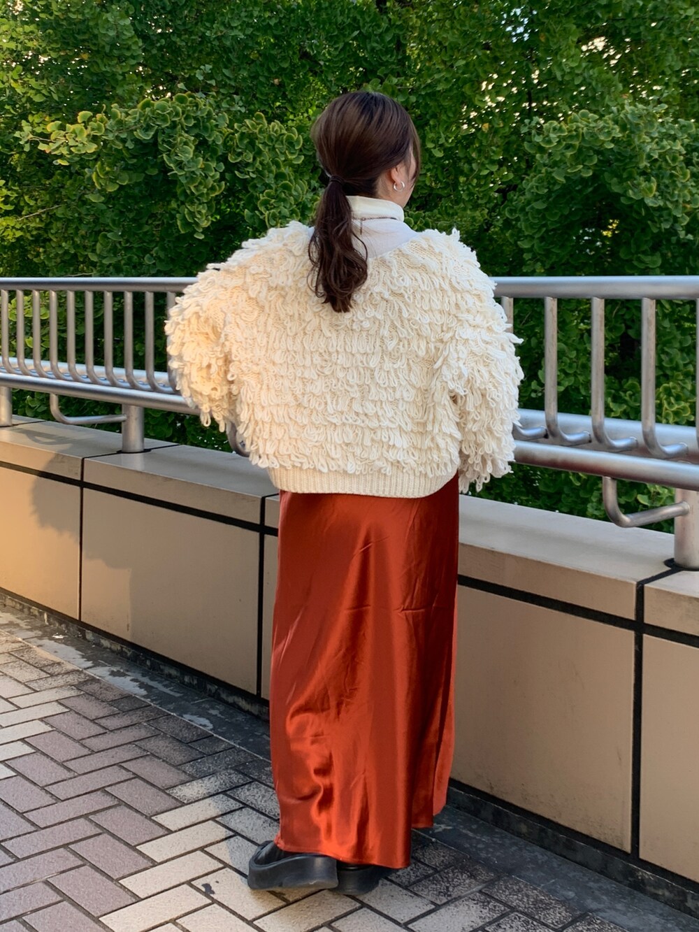 ホワイト系のカーディガン/ボレロ、ホワイト系のTシャツ/カットソー、オレンジ系のスカートを着用したレディースの冬コーディネートの3枚目の写真