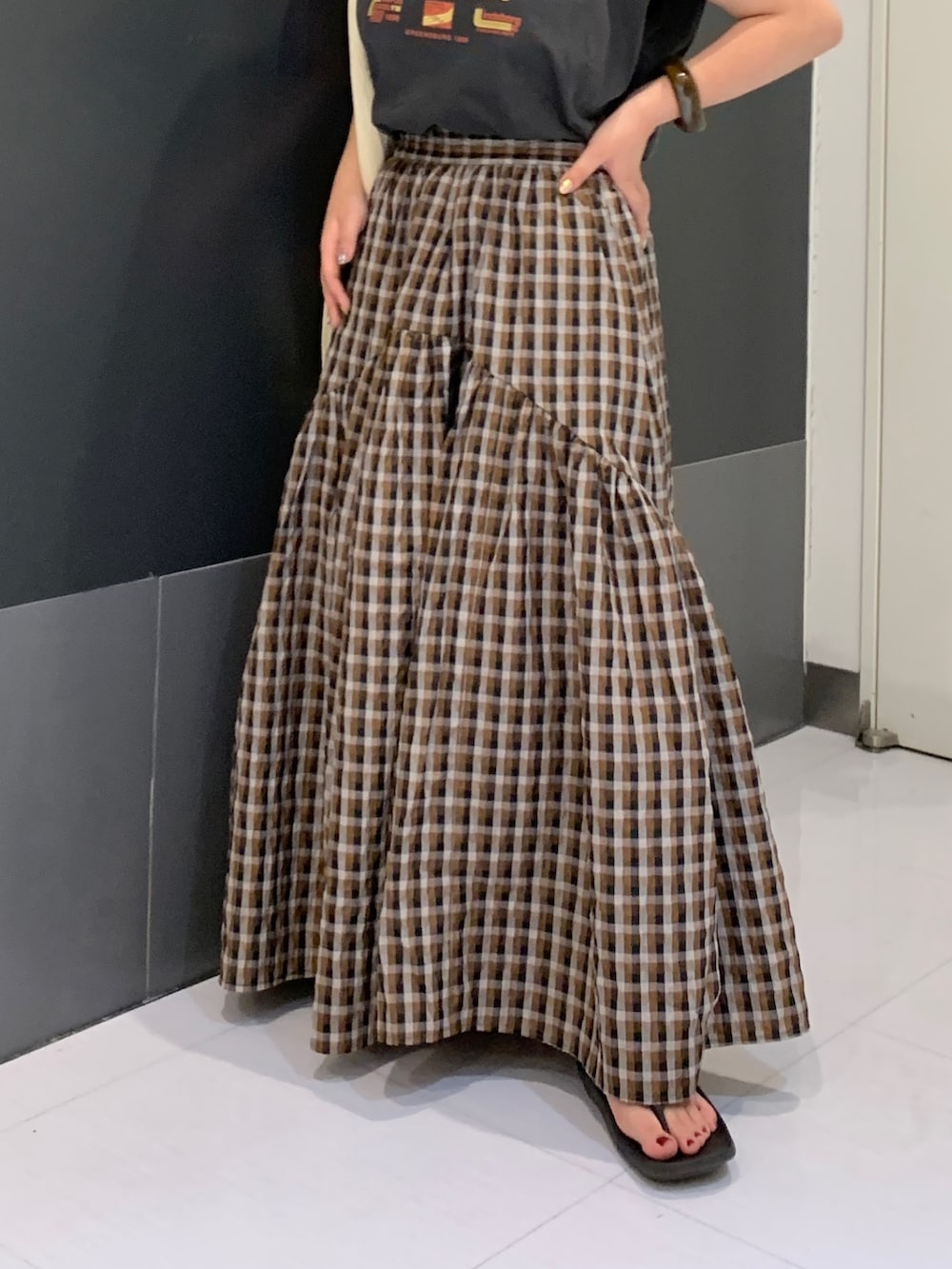 グレー系のタンクトップ、ブラウン系のスカート、ホワイト系のトートバッグを着用したレディースの夏コーディネートの4枚目の写真