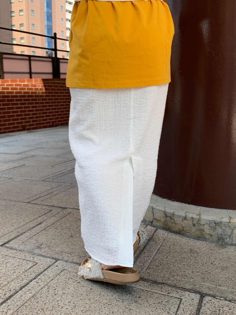 イエロー系のTシャツ/カットソー、ホワイト系のスカート、ホワイト系のキャミソールを着用したレディースの夏コーディネートの7枚目の写真