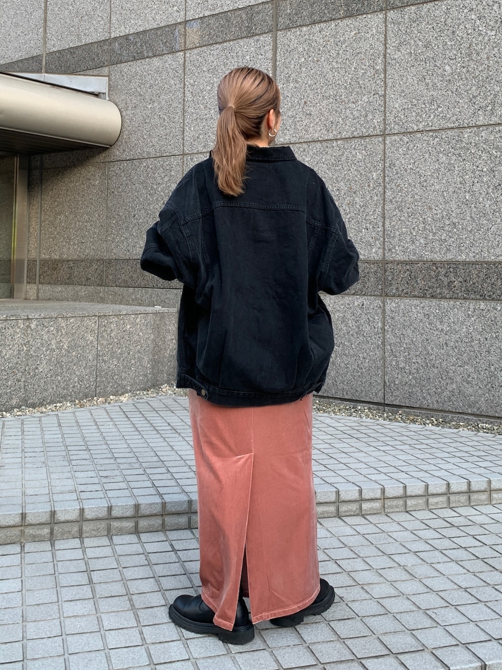 ブラック系のデニムジャケット、オレンジ系のワンピースを着用したレディースの秋コーディネートの3枚目の写真