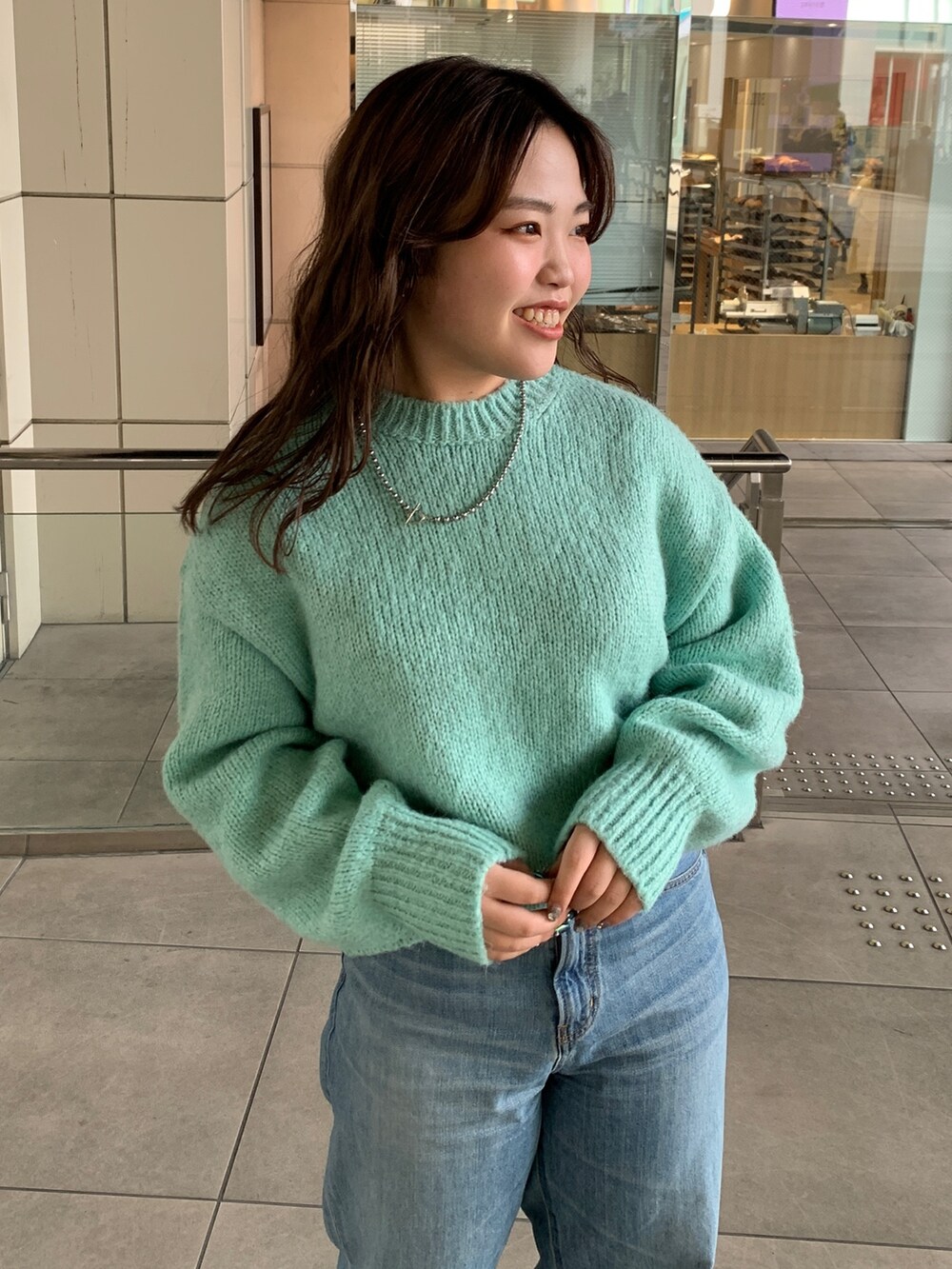 ブラック系のダウンジャケット/コート、グリーン系のニット/セーター、ブルー系のデニムパンツを着用したレディースの冬コーディネートの7枚目の写真