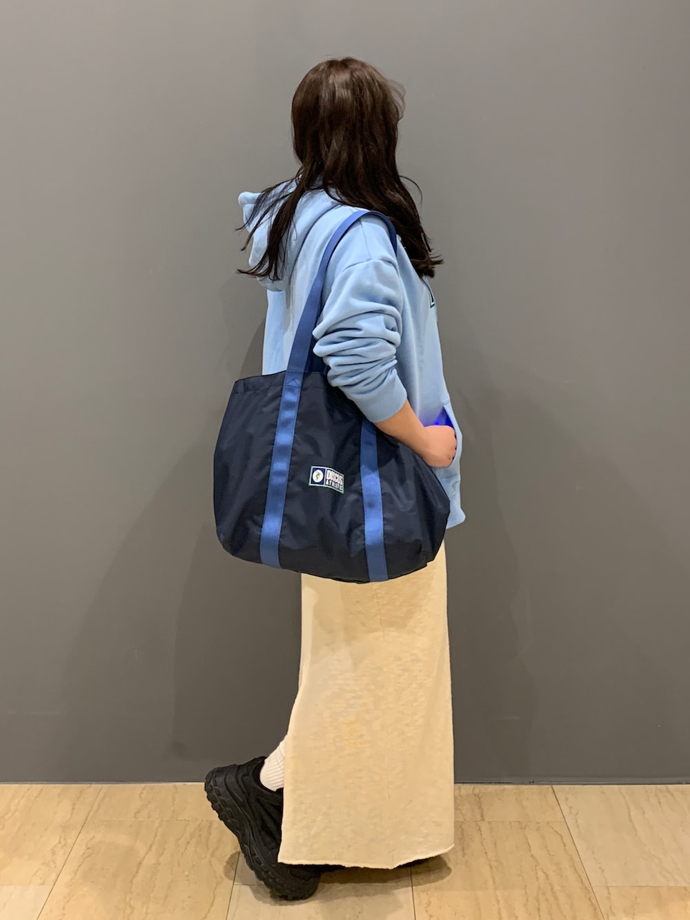 ブルー系のパーカー、ホワイト系のスカート、ブルー系のトートバッグを着用したレディースの冬コーディネートの2枚目の写真