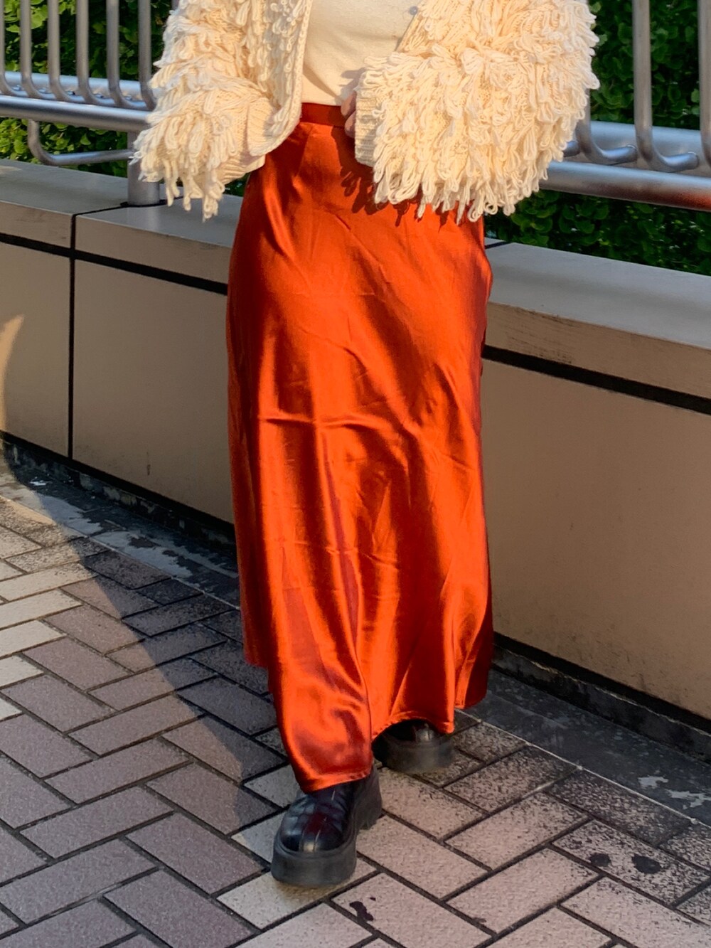 ホワイト系のカーディガン/ボレロ、ホワイト系のTシャツ/カットソー、オレンジ系のスカートを着用したレディースの冬コーディネートの5枚目の写真