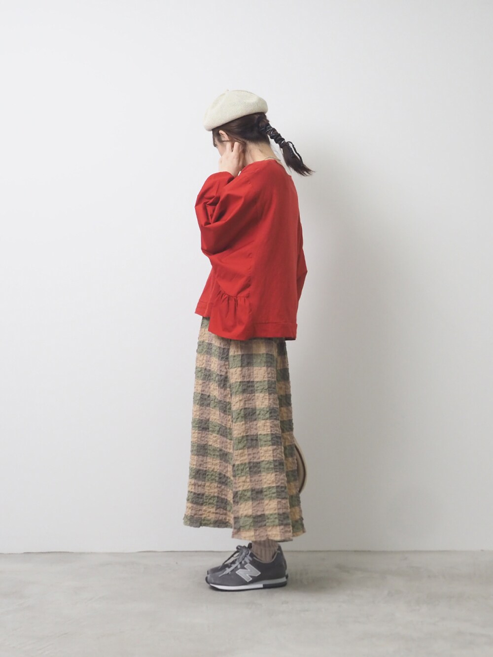 レッド系のTシャツ/カットソー、ベージュ系のスカート、グレー系のスニーカーを着用したレディースの夏コーディネートの2枚目の写真