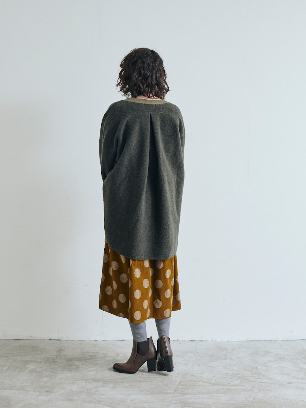 グリーン系のノーカラージャケット、イエロー系のワンピースを着用したレディースの秋コーディネートの2枚目の写真