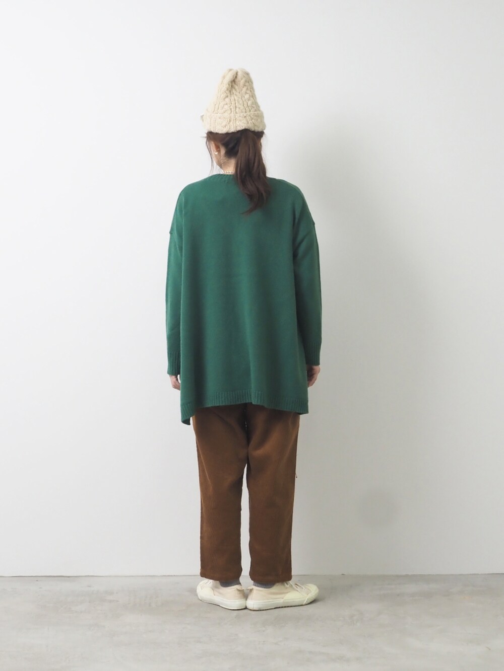 グリーン系のカーディガン/ボレロ、ブラウン系のパンツを着用したレディースの秋コーディネートの2枚目の写真