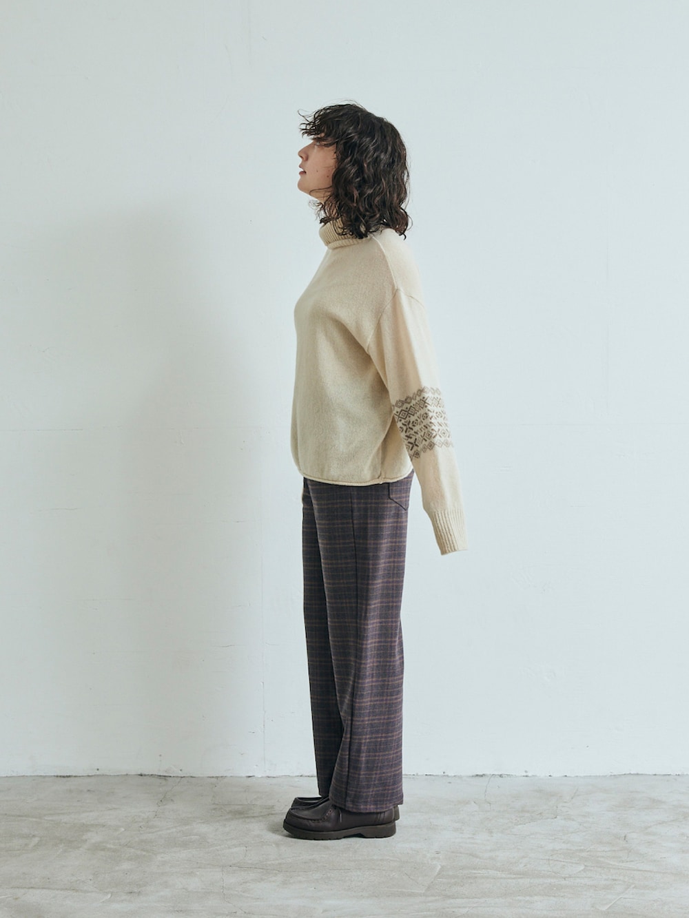 ベージュ系のニット/セーター、ブラウン系のスラックスを着用したレディースの秋コーディネートの2枚目の写真