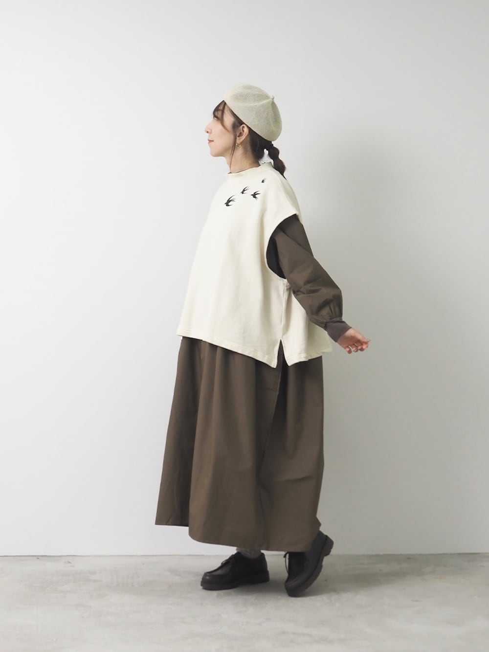 グレー系のベスト、ブラウン系のワンピース/ドレス、ブラック系のショルダーバッグを着用したレディースの秋コーディネートの2枚目の写真