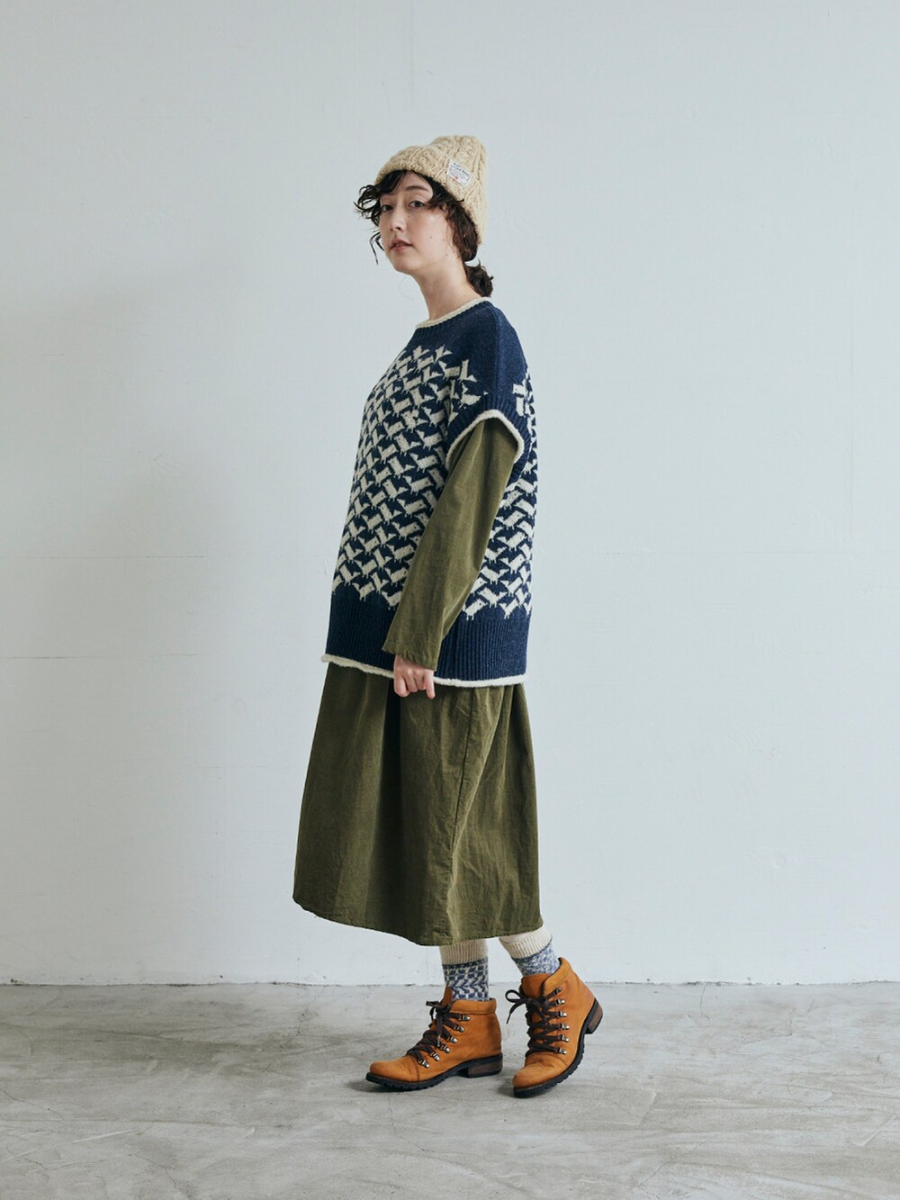 ブルー系のベスト、グリーン系のワンピースを着用したレディースの秋コーディネートの2枚目の写真