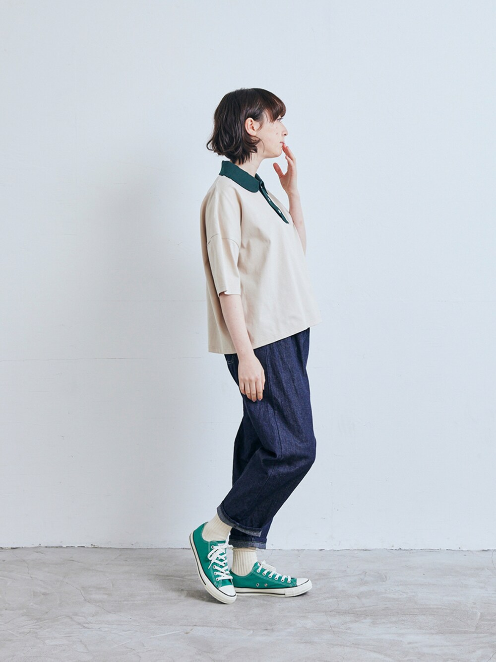 ベージュ系のポロシャツ、ブルー系のデニムパンツを着用したレディースの春コーディネートの2枚目の写真