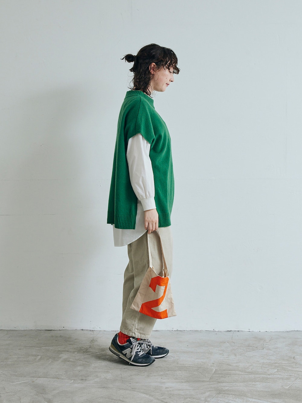 グリーン系のベスト、ベージュ系のパンツを着用したレディースの秋コーディネートの2枚目の写真