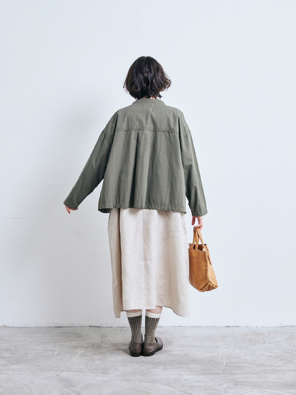 グリーン系のノーカラージャケット、ベージュ系のワンピース/ドレスを着用したレディースの春コーディネートの2枚目の写真