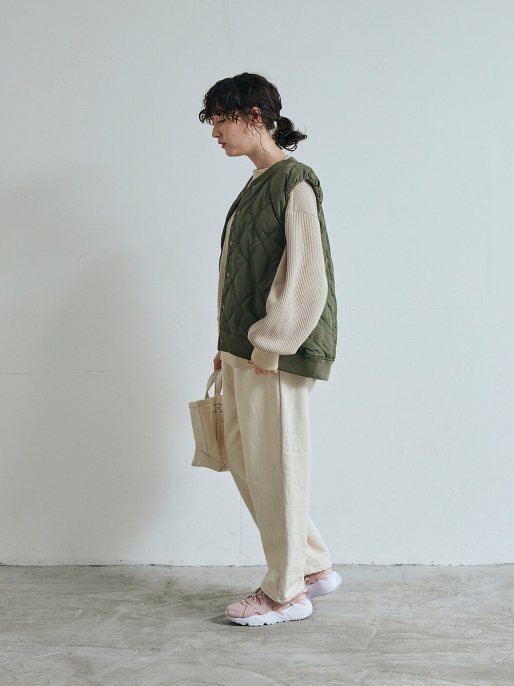 ベージュ系のスウェット、ホワイト系のデニムパンツ、グリーン系のベストを着用したレディースの秋コーディネートの2枚目の写真