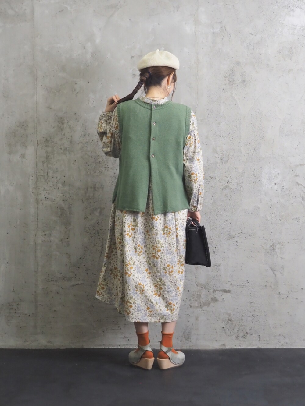 グリーン系のベスト、ベージュ系のワンピース、ブルー系のサンダルを着用したレディースの秋コーディネートの2枚目の写真