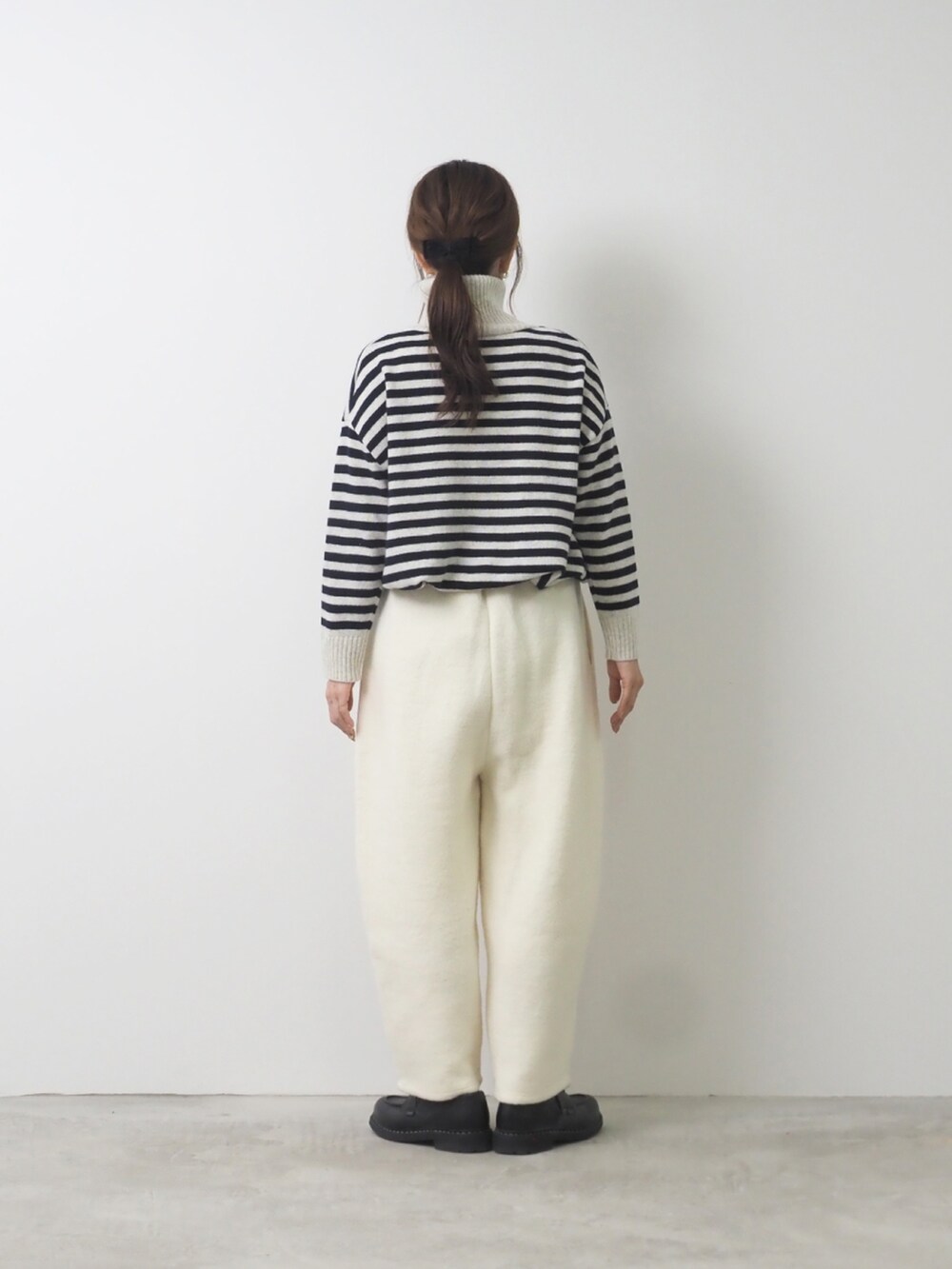 グレー系のニット/セーター、ホワイト系のパンツを着用したレディースの秋コーディネートの2枚目の写真