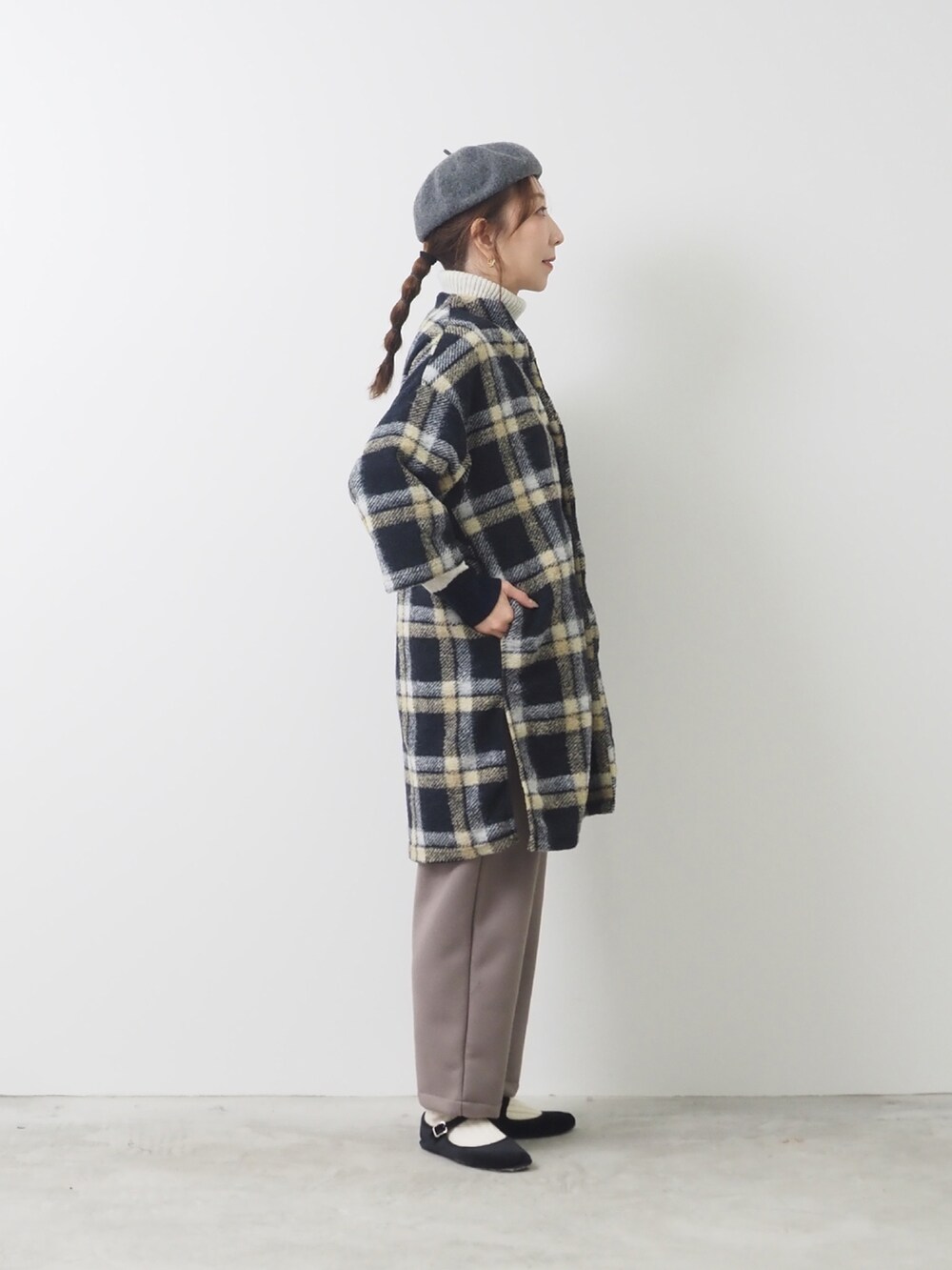 ブラック系のノーカラーコートを着用したレディースの秋コーディネートの2枚目の写真