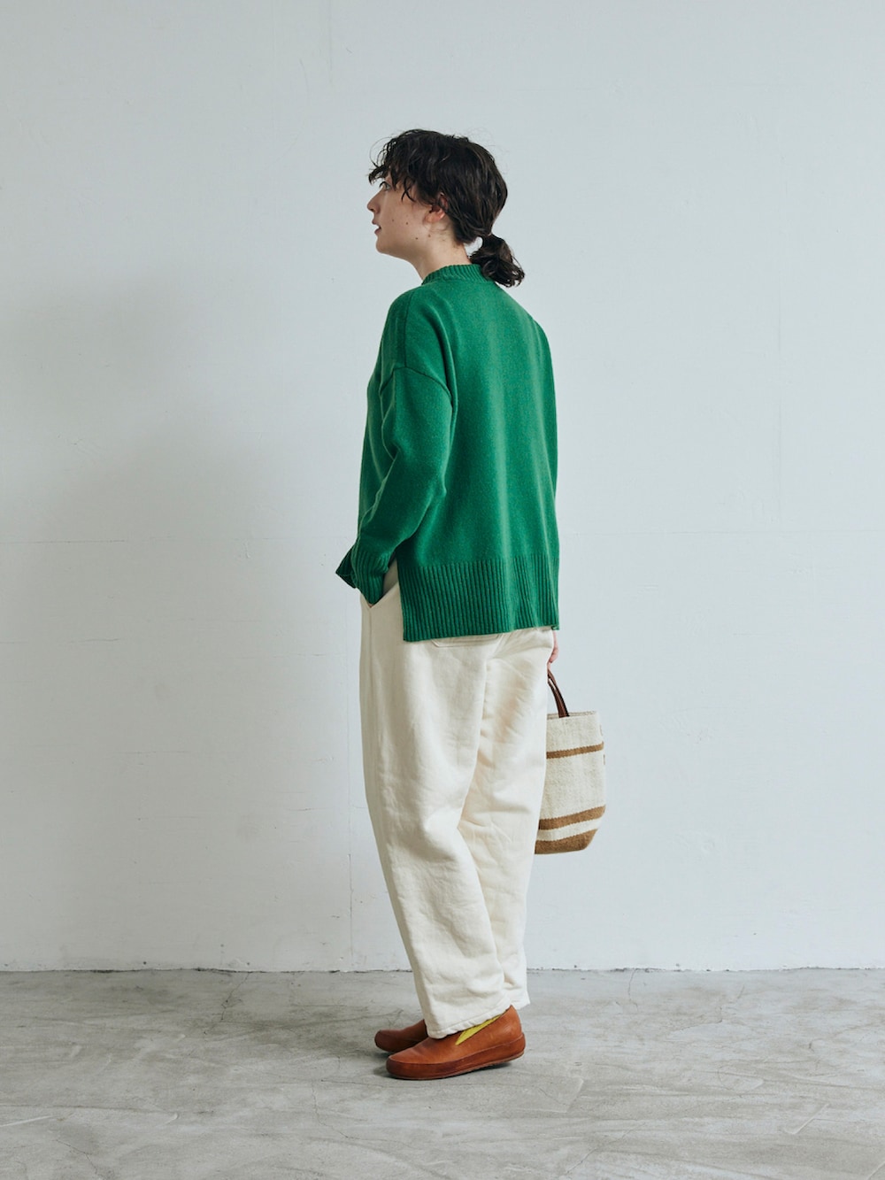 グリーン系のニット/セーター、ホワイト系のデニムパンツを着用したレディースの秋コーディネートの2枚目の写真